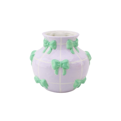 Vaso lilás arredondado com laços verdes decorativos.