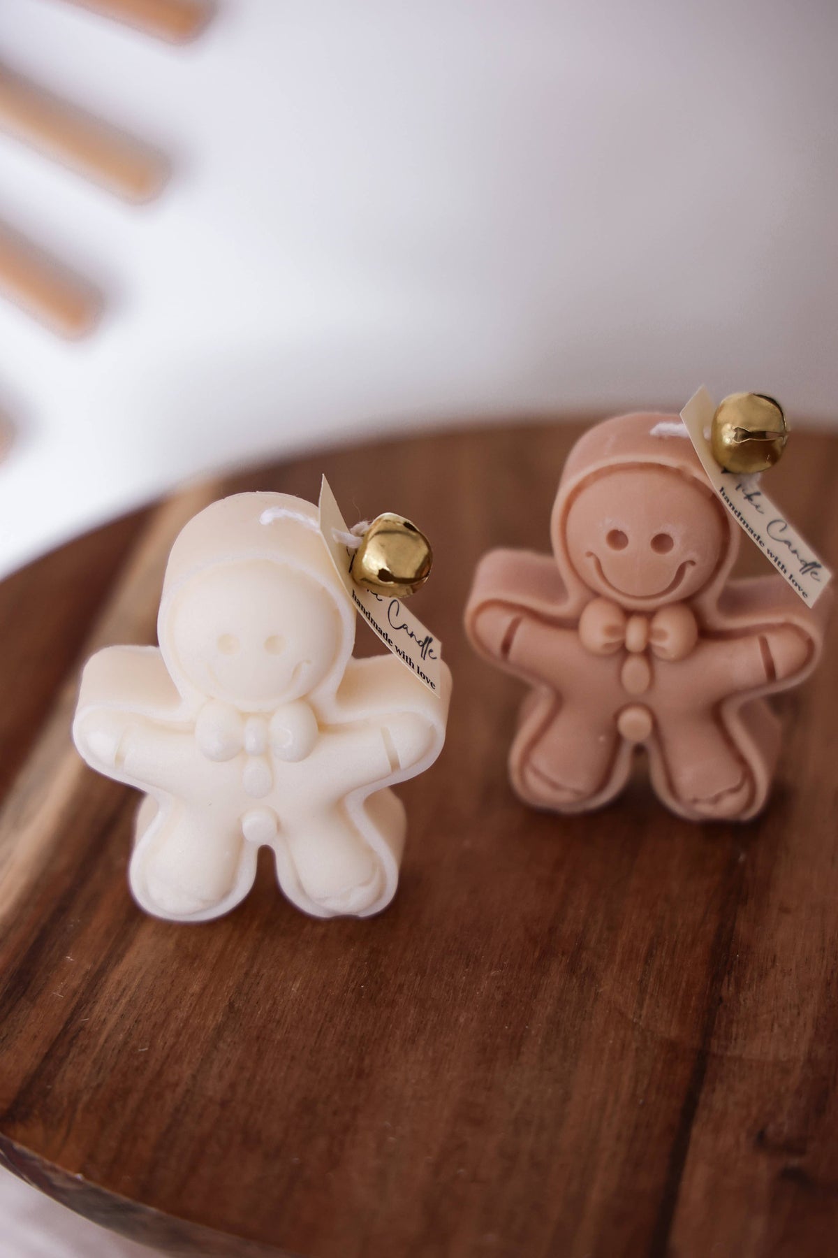 Vela artesanal em forma de boneco de gengibre sobre tabuleiro decorativo.