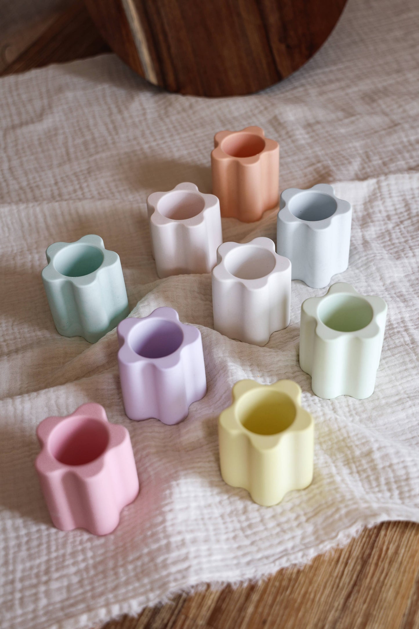 Suporte em gesso para vela alta em tons pastel sobre tecido suave.